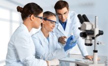3 Scientists in laboratory with white lab coats and protective glasses